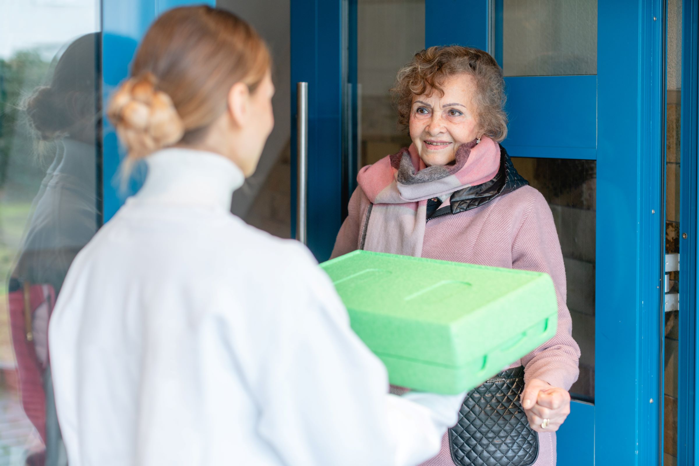 Volunteer delivering a meal to the door of a senior citizen.